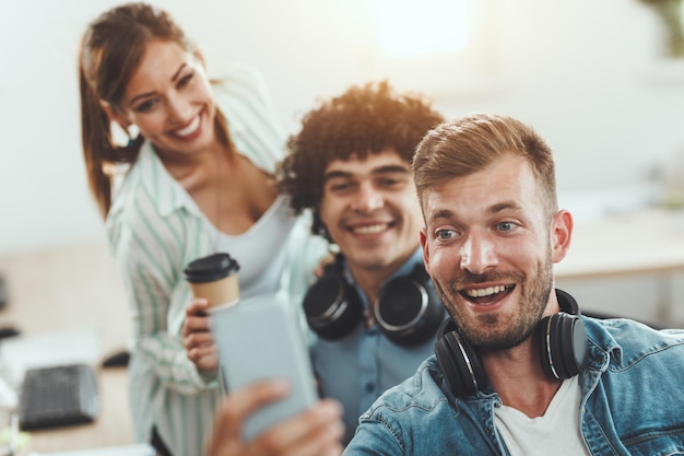 Team of three cheerful freelancers taking a selfie while working in the creative office.