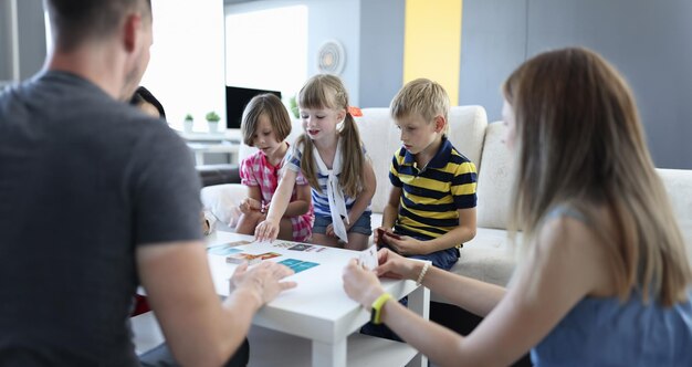 Team of three children and team of three adults play board games at home