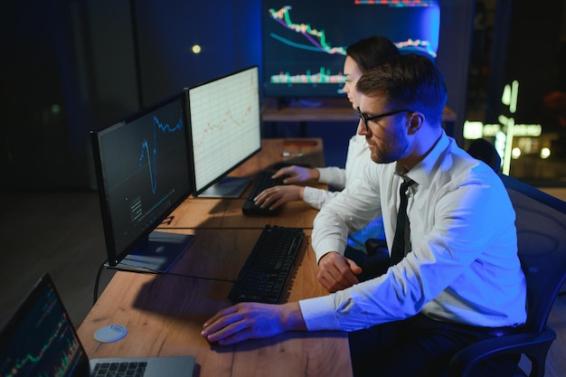 Foto gruppo di commercianti che lavorano al monitor del computer e navigano online nell'ufficio di negoziazione