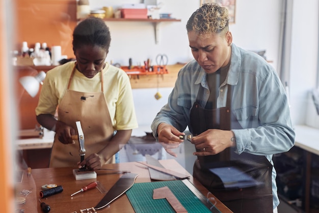 워크샵에서 수제 가죽 조각을 만드는 두 명의 현대 장인 팀