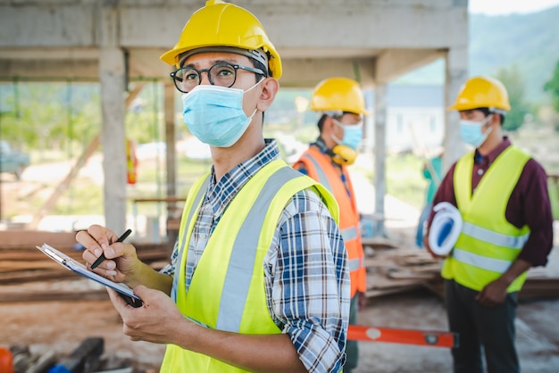 Team van bouwingenieurs en drie architecten staan klaar om medische maskers te dragen. corona of covid-19 dragen maskers tijdens het ontwerp van de constructie.