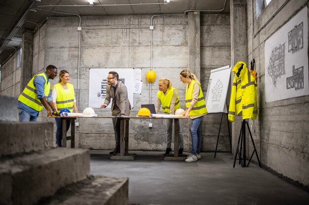 Team van bouwkundig ingenieurs en architecten die plannen en blauwdrukken analyseren op de bouwplaats