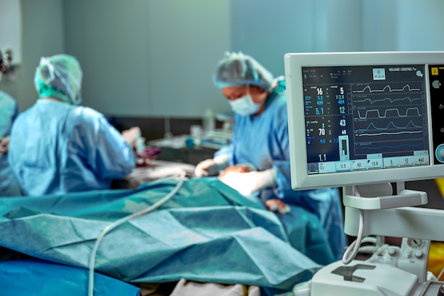 Team van chirurgen voor werk in de operatiekamer. Verschillende chirurgen voeren een operatie uit in een echte operatiekamer. Blauw licht, wit handschoenen verticaal schot.