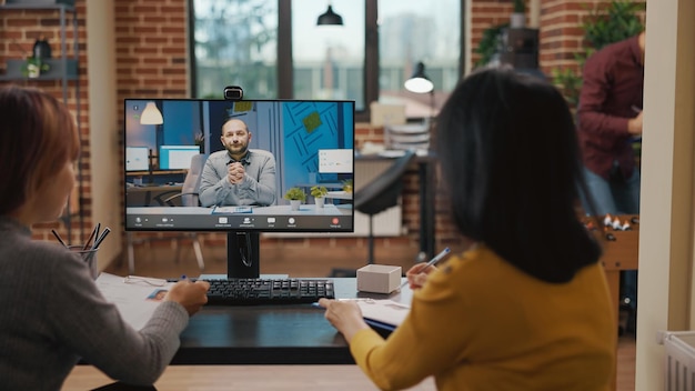 Team van collega's die een man ontmoeten tijdens een online videogesprek tijdens een sollicitatiegesprek. Aziatische vrouwen die een wervingsgesprek bijwonen met een kandidaat, gebruiken een videoconferentie op afstand om te discussiëren over werving.