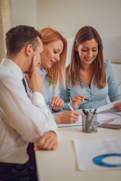 Team van drie jonge professionals werkt nauw samen aan wederzijds project op kantoor.