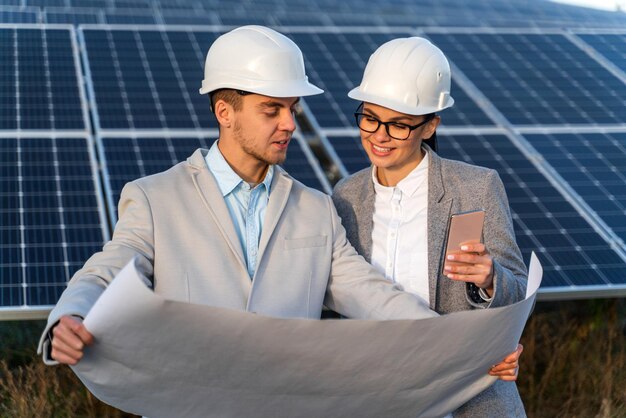 Team van industriële technici ruzie met het schema van zonnepanelen op het platteland