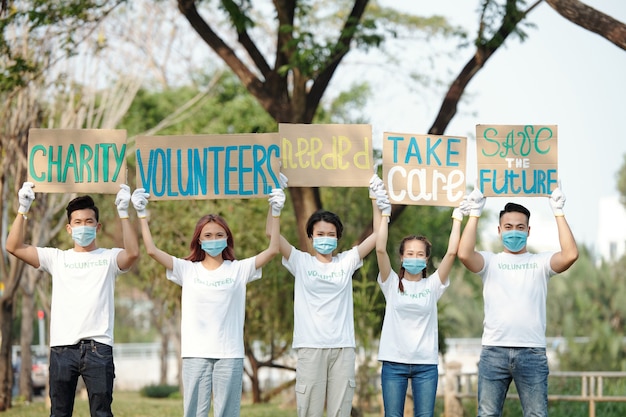 Team van jonge Aziatische vrijwilligers die borden boven hun hoofden steken bij het promoten van liefdadigheidsorganisaties