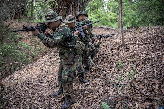 Team van legersoldaat met machinegeweer die zich in het bos bewegenThaise militiemilitair in gevechtsuniformen in het bosDwaal door de patrouille die in het regenwoud afloopt