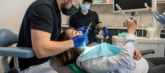 Team van medische tandartsen in een tandartspraktijk die met een patiënt praat en zich voorbereidt op de behandeling van het tandenpoetsen van de patiënt