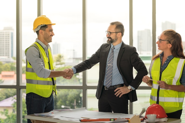 Team van multi-etnische architecten bezig met bouwplannen in de vergaderruimte