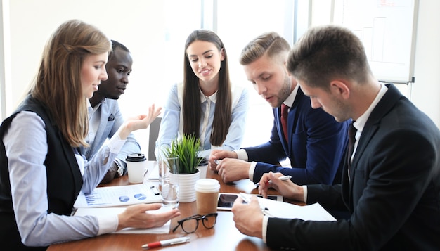 Team van zakenmensen die discussie hebben aan tafel in creatief kantoor.