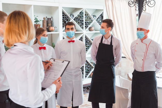 A team of waiters conduct a briefing on the summer terrace of the restaurant.