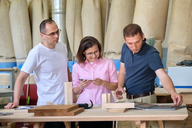 Team of woodworking workshop workers are discussing. Group of people client, designer or engineer and workers discuss work, background carpentry production