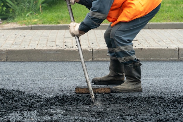 A team of workers on the road during the laying of new asphalt\
at the construction site asphalt laying equipment and workers with\
shovels and in special clothes road surface repair