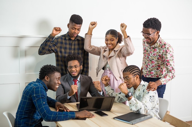 team of young african people working in office at table with laptop