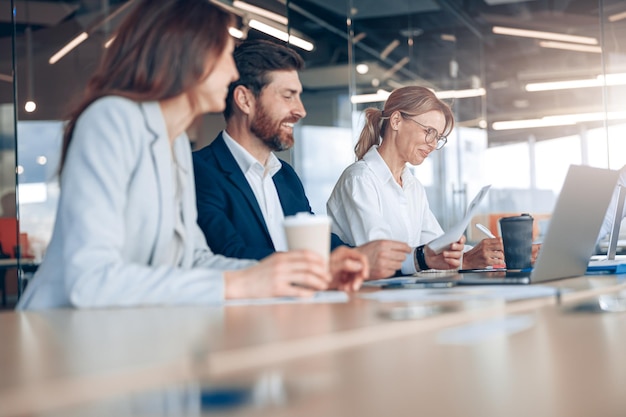 Team of young businessmen communicating together during meeting and drink coffee in modern office