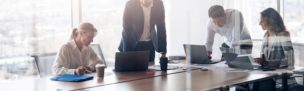 Team of young businessmen working and communicating together in office with panoramic windows