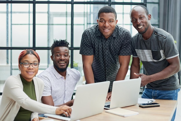 a team of young designers at work in the office posing for the camera while sitting at the table