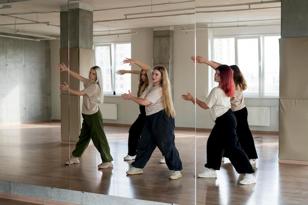 Photo team of young female dancers practice choreography in the studio in front of the mirror