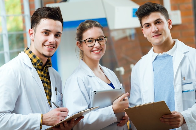 Team of young professional scientists looking at camera in laboratory.