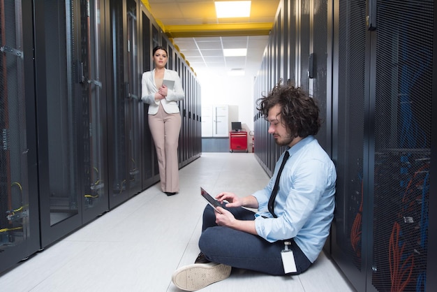 Photo team of young technicians working together on servers at the data center using tablet computers