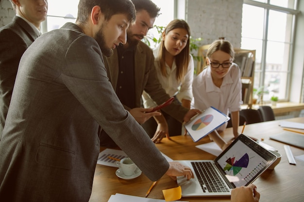 Teambuilding. Group of young business professionals having a meeting. Diverse group of coworkers discuss new decisions, plans, results, strategy. Creativity, workplace, business, finance, teamwork.