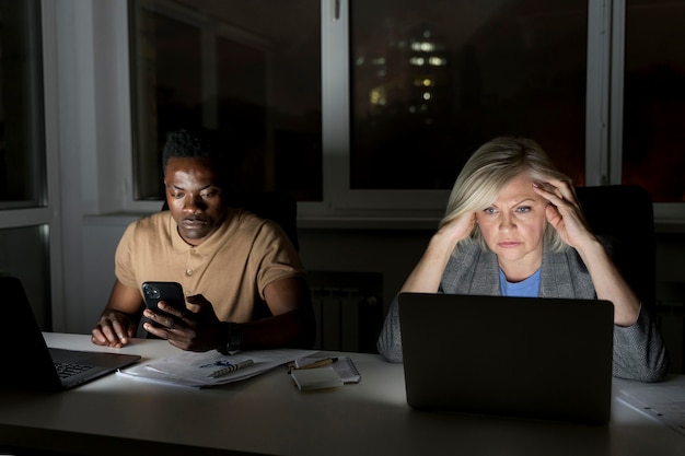 Foto compagni di squadra che lavorano fino a tardi in ufficio