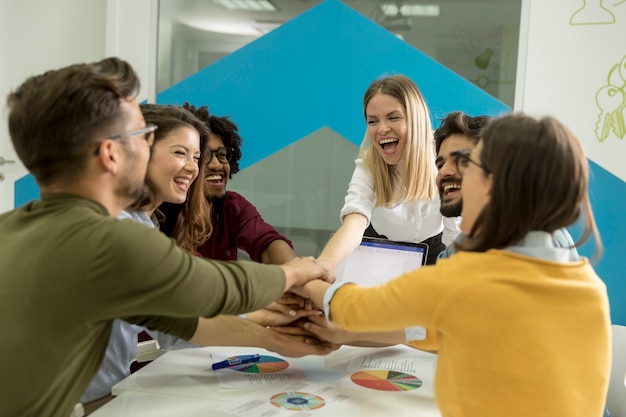 Teammensen stapelen handen samen over tafel bezig met teambuilding