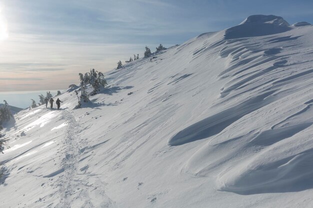 Teamwandelingen op alpine berglandschap met witte sneeuw en dramatische bewolkte hemel