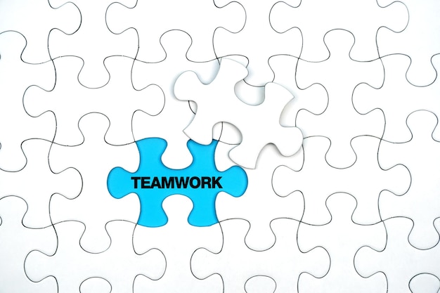 Teamwork concept Teamwork word on white puzzle piece on blue background