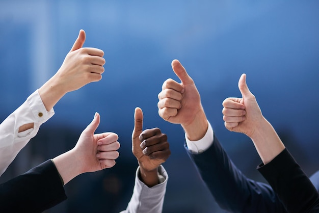 Teamwork trumps all Shot of a group of office workers giving thumbs up together