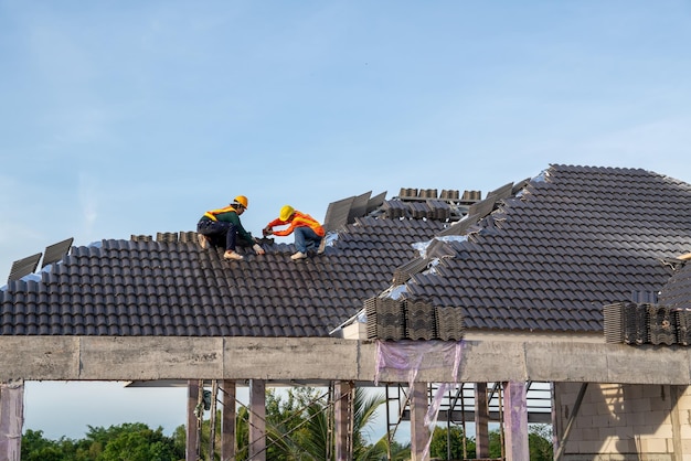 Teamwork van een bouwvakker installeert nieuw dak Elektrische boor gebruikt op nieuwe daken met betonnen dakpannen Dakbedekkingsgereedschap Selectieve focus van betonnen dakpannen