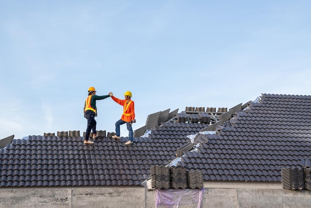 Teamwork van een bouwvakker installeert nieuw dak Elektrische boor gebruikt op nieuwe daken met betonnen dakpannen Dakbedekkingsgereedschap