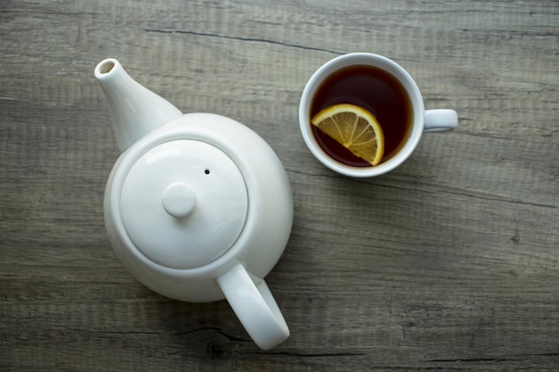 Teapot and cup of black tea with lemon