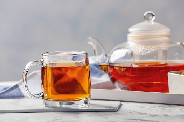 Teapot and cup of hot beverage on table