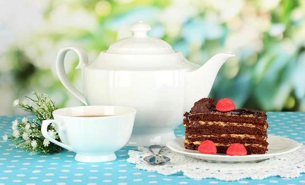 Teapot cup of tea and delicious cake on natural background