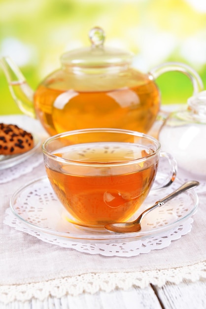 Teapot and cup of tea on table on bright background