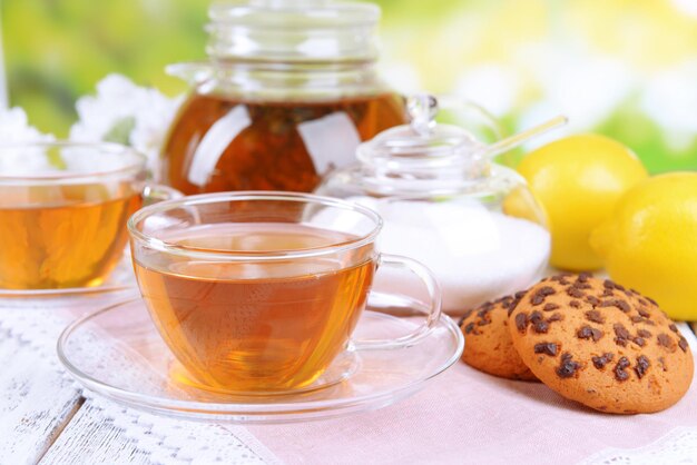 Teapot and cups of tea on table on bright background