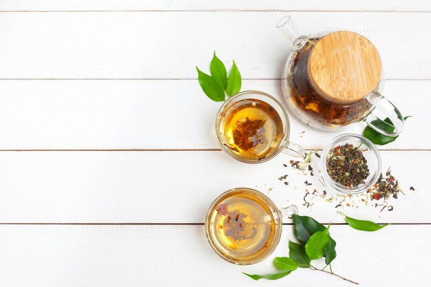 Teapot and cups of tea on a white wooden background