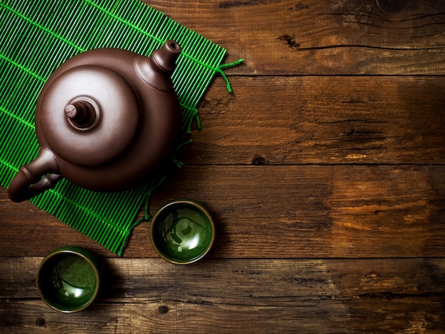Teapot on green bamboo mat. Top view