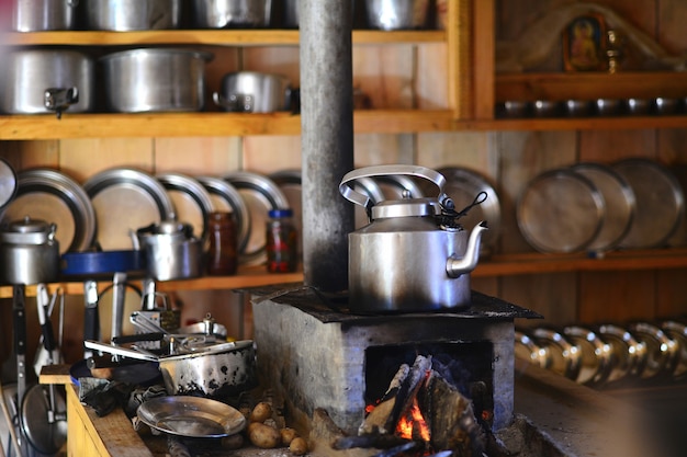 Teapot in high mountain kitchen with fire and utensils in Nepal.