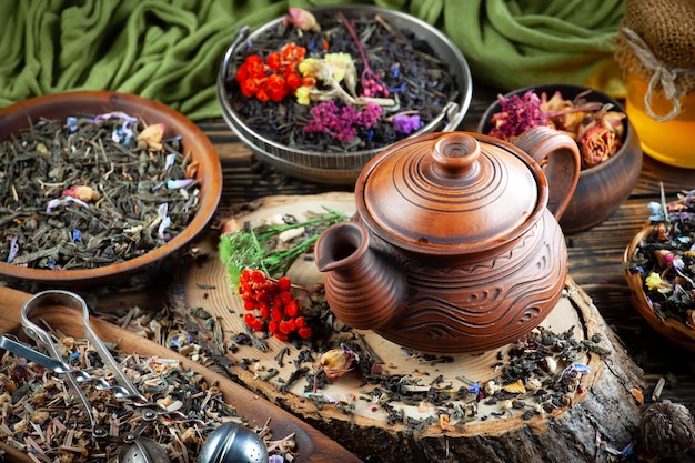 A teapot is on a table with other teas and flowers.