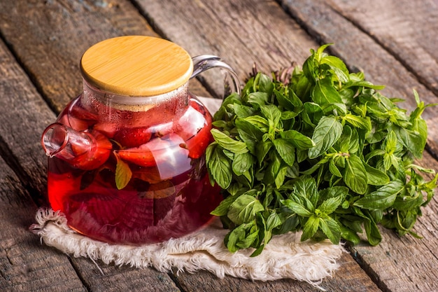 Foto teiera di tè rosso alla frutta estiva e foglie di menta