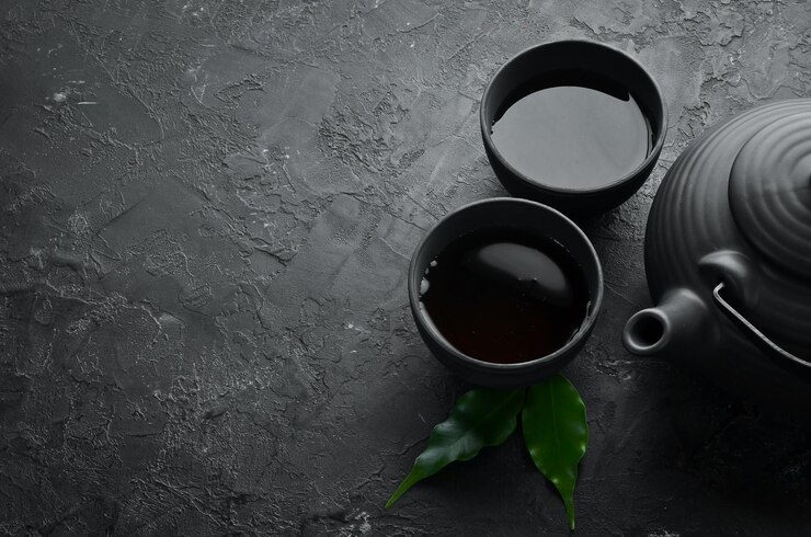 검은 돌 배경 위에 있는 찻주전자와 차 두 잔 텍스트를 위한 위쪽 보기 여유 공간