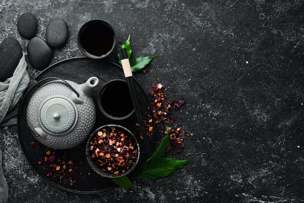 Teapot and two cups of tea on a black stone background Top view free space for your text