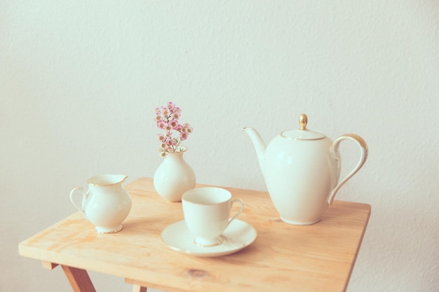 Photo teapot wit cup and flower vase on table at home