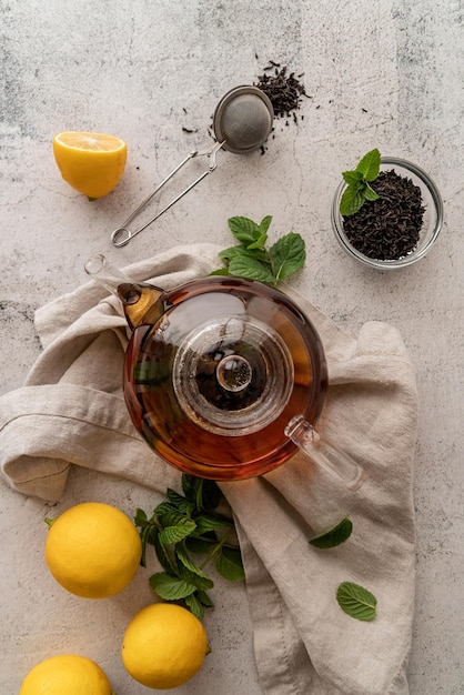 teapot with black tea decorated with mint leaves lemons and dry tea leaves top view flat lay