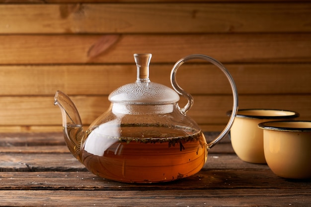 Teapot with brewed hot tea on a wooden, cozy background