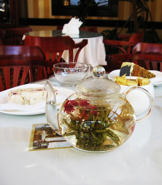 Teapot with tea and dessert on the table in the cafe photo