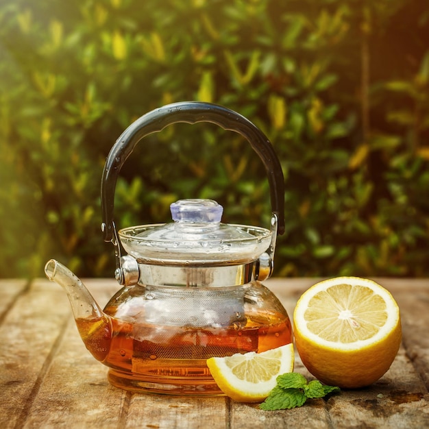 Teapot with tea and a lemon on a wooden board